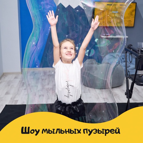 Девочка внутри гигантского мыльного пузыря на детском празднике
